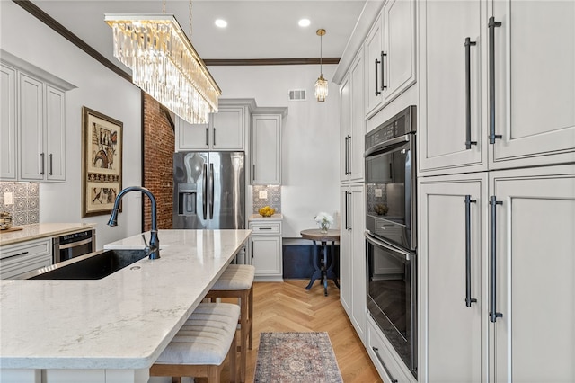 kitchen with stainless steel refrigerator with ice dispenser, a kitchen bar, crown molding, hanging light fixtures, and light parquet flooring