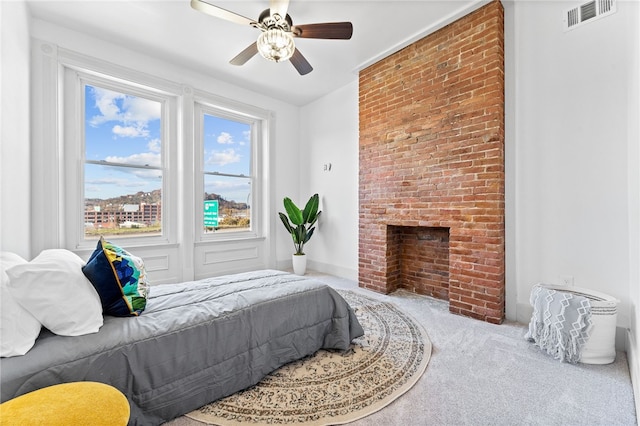 carpeted bedroom with a fireplace and ceiling fan