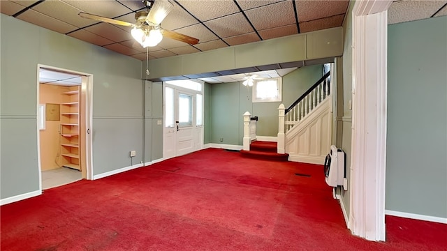 basement with a drop ceiling, ceiling fan, and carpet