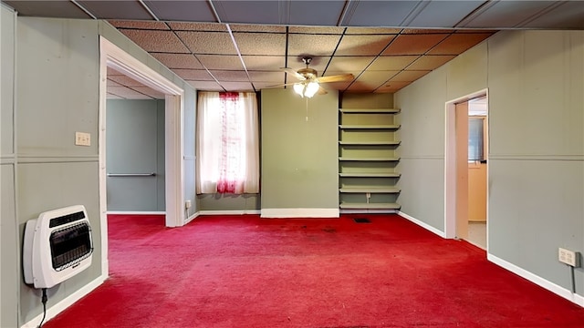 interior space featuring a paneled ceiling, carpet flooring, heating unit, and ceiling fan