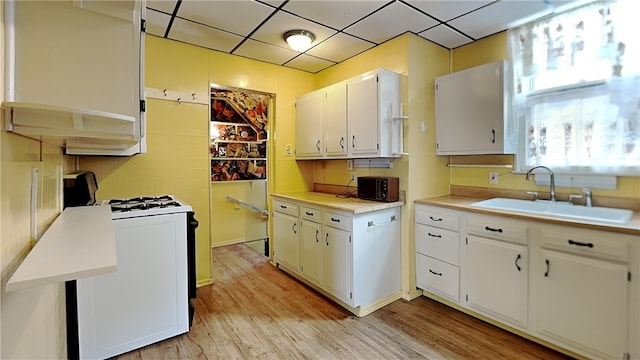 kitchen with sink, white gas range oven, white cabinetry, a drop ceiling, and light wood-type flooring