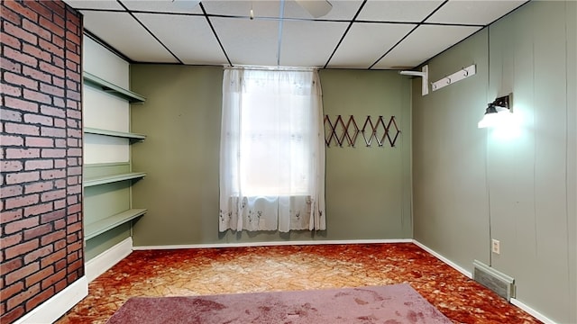 empty room with brick wall and a paneled ceiling