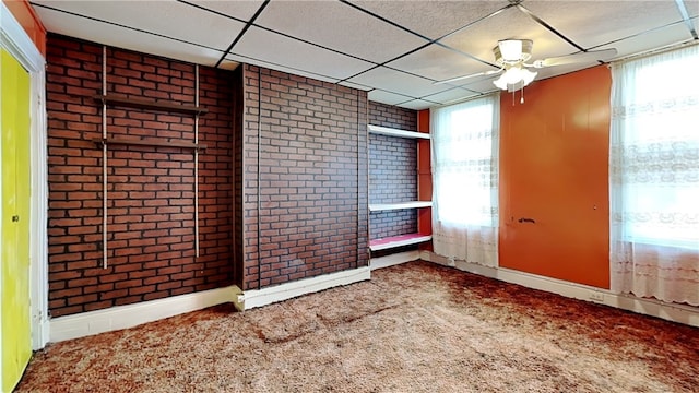 spare room featuring ceiling fan, a paneled ceiling, brick wall, and carpet flooring