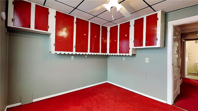 basement featuring ceiling fan, a drop ceiling, and dark carpet