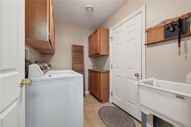 washroom with cabinets, light tile patterned floors, a textured ceiling, and washer and clothes dryer