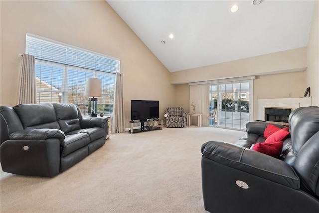 living room with a premium fireplace, carpet, a healthy amount of sunlight, and high vaulted ceiling