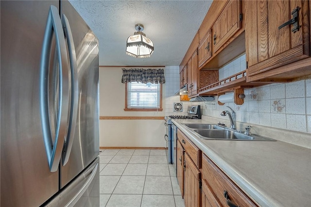 kitchen with sink, light tile patterned floors, backsplash, stainless steel appliances, and a textured ceiling