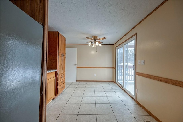 kitchen featuring crown molding, refrigerator, a textured ceiling, and light tile patterned floors