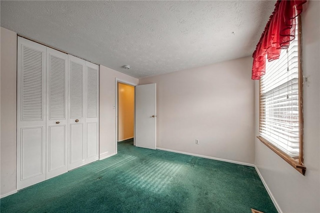 unfurnished bedroom featuring a textured ceiling, dark carpet, and a closet