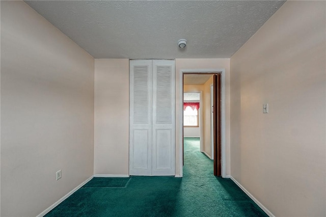 unfurnished room featuring a textured ceiling and dark colored carpet