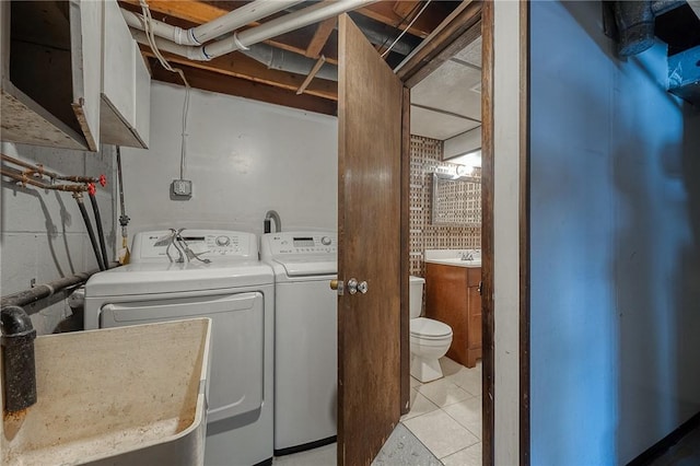 laundry room featuring cabinets, washing machine and clothes dryer, sink, and light tile patterned floors