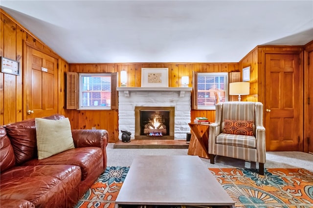 living room with a fireplace, light carpet, and wood walls