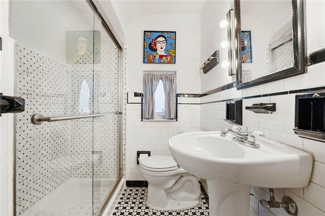 bathroom with walk in shower, toilet, and tile walls