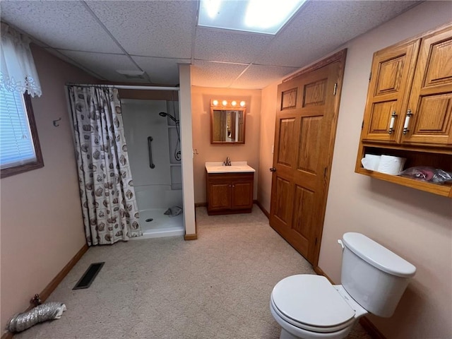 full bathroom featuring a shower stall, toilet, a drop ceiling, vanity, and baseboards