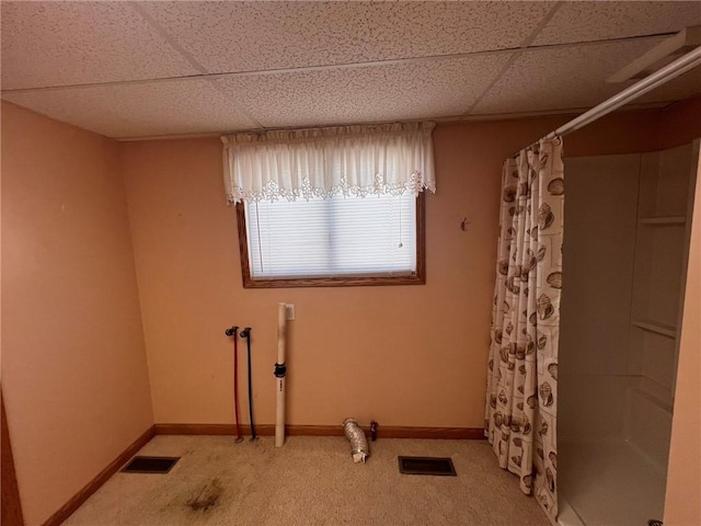 spare room with a paneled ceiling, light carpet, and baseboards