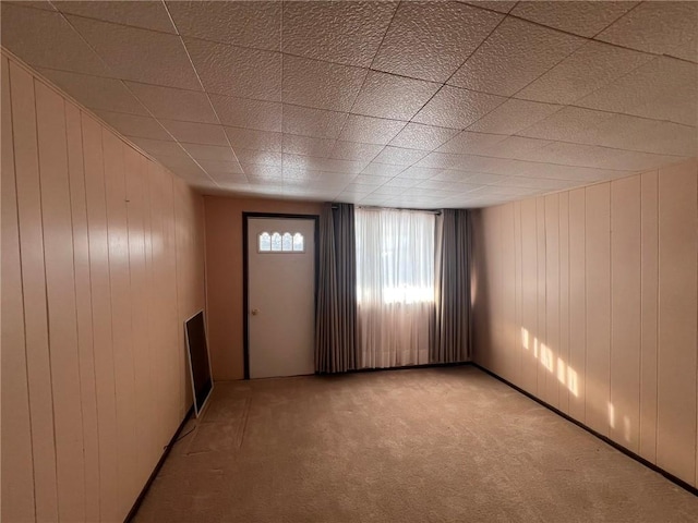 carpeted spare room with wood walls