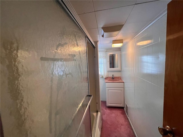 hallway with carpet floors, sink, and tile walls