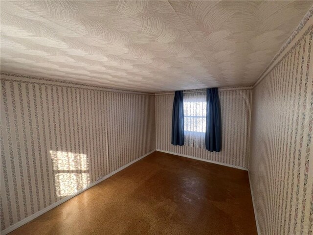unfurnished room featuring wallpapered walls, baseboards, and a textured ceiling