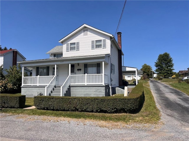 view of front of home featuring a chimney and covered porch