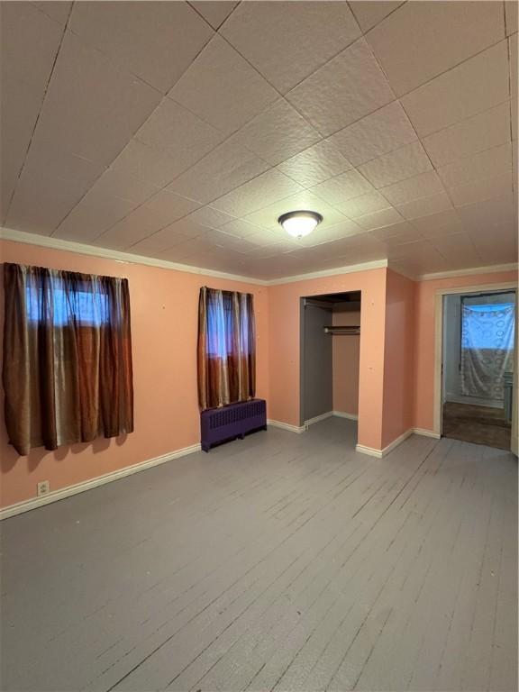 unfurnished bedroom featuring hardwood / wood-style flooring, radiator heating unit, and ornamental molding