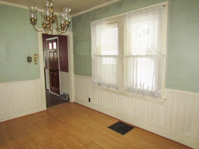 entryway featuring hardwood / wood-style floors, plenty of natural light, ornamental molding, and a chandelier