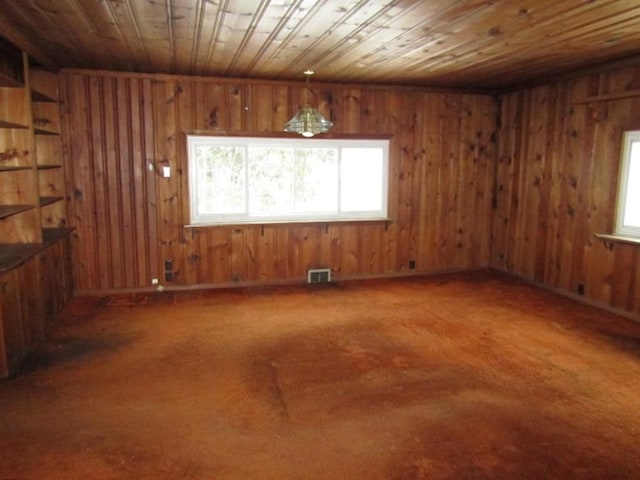 empty room with wood ceiling, plenty of natural light, and wooden walls