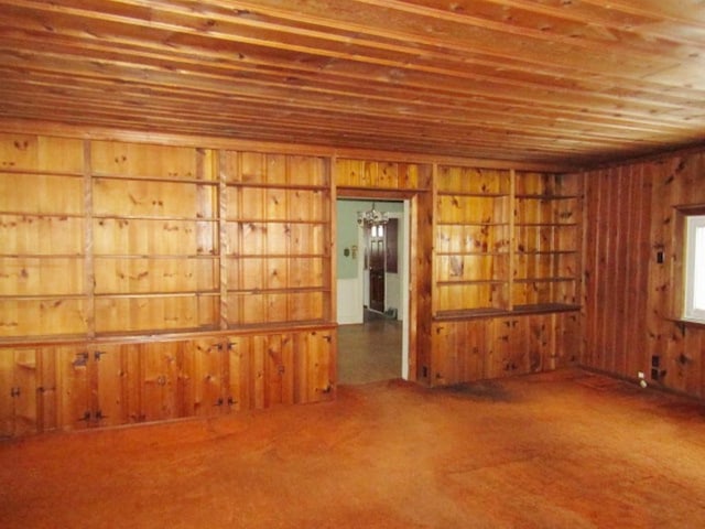 carpeted spare room with wood ceiling and wooden walls