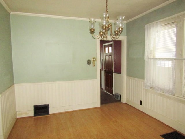 spare room with an inviting chandelier, ornamental molding, and wood-type flooring