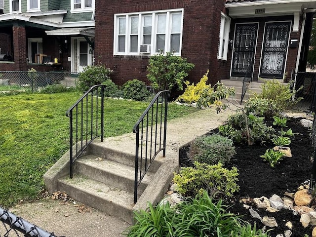 entrance to property featuring cooling unit and a lawn