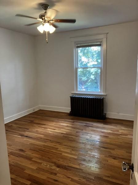 empty room with radiator heating unit, dark hardwood / wood-style floors, and ceiling fan