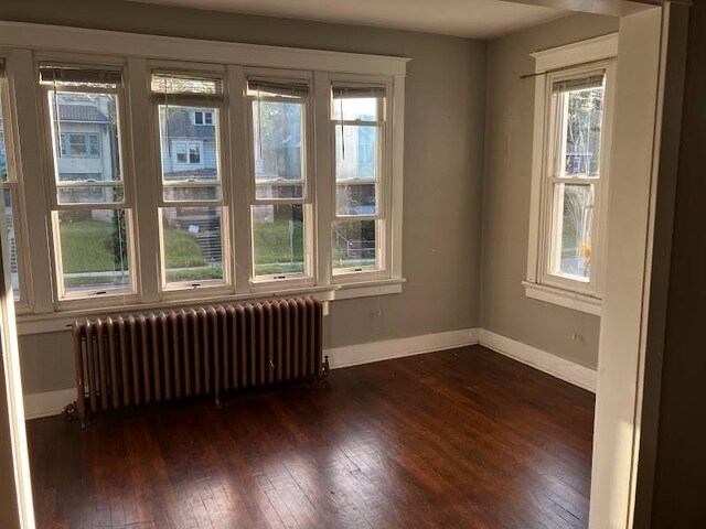 unfurnished room with dark wood-type flooring and radiator heating unit