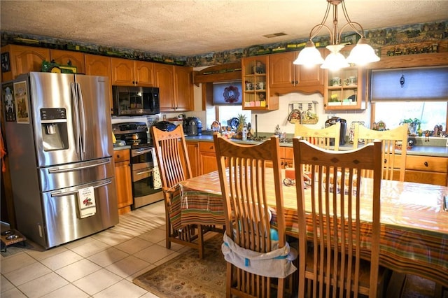 kitchen featuring light tile patterned flooring, decorative light fixtures, a textured ceiling, appliances with stainless steel finishes, and a notable chandelier