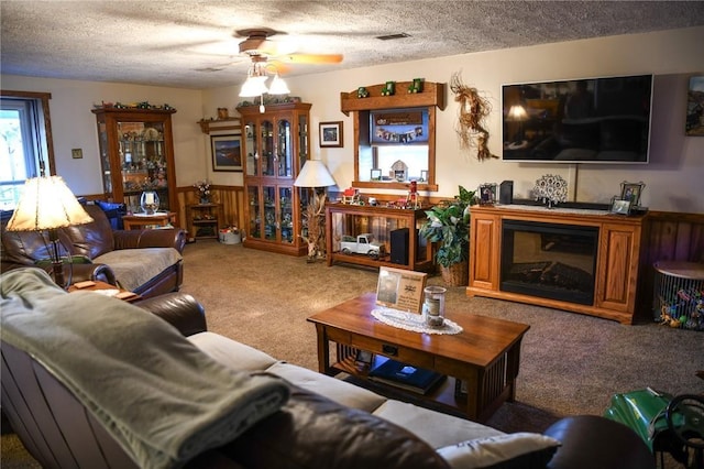 living room featuring ceiling fan, carpet floors, and a textured ceiling