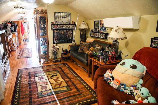 interior space with vaulted ceiling, a wall mounted AC, a textured ceiling, and light wood-type flooring