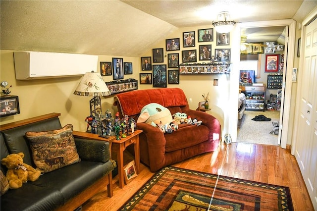 sitting room with lofted ceiling, hardwood / wood-style floors, and a textured ceiling