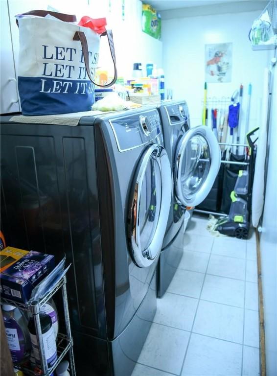 laundry room featuring washing machine and dryer and light tile patterned floors