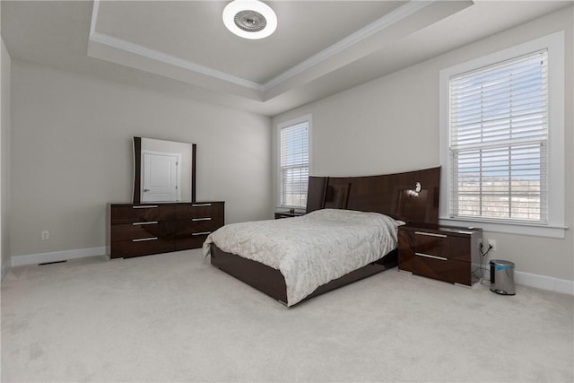 carpeted bedroom featuring multiple windows, ornamental molding, and a raised ceiling