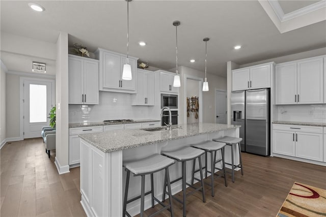 kitchen with sink, hanging light fixtures, an island with sink, stainless steel appliances, and white cabinets