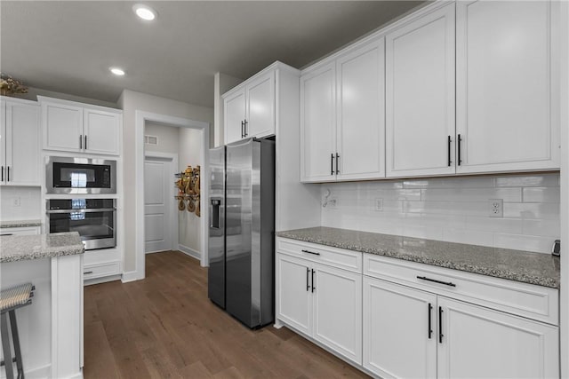 kitchen featuring backsplash, stainless steel appliances, light stone countertops, white cabinets, and dark hardwood / wood-style flooring