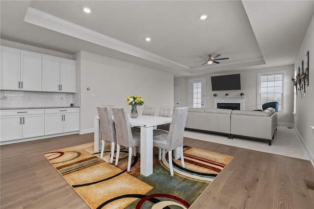 dining room featuring a raised ceiling, crown molding, dark hardwood / wood-style floors, and ceiling fan