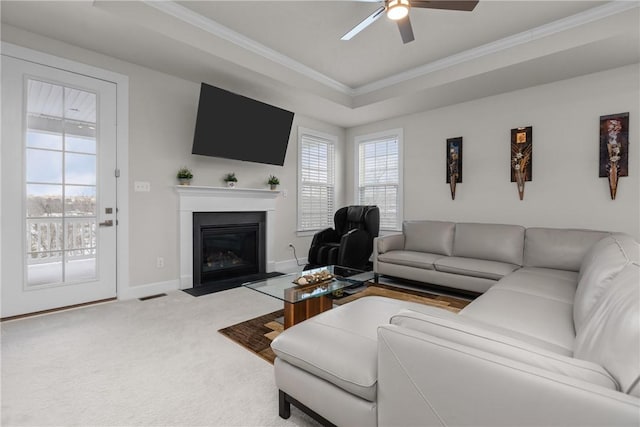 living room featuring ornamental molding, light colored carpet, ceiling fan, and a tray ceiling