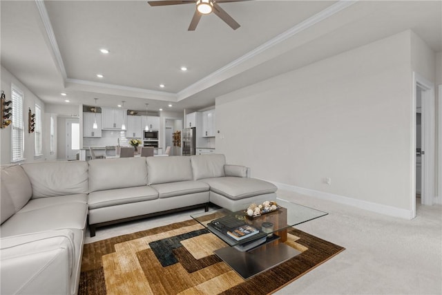 carpeted living room featuring crown molding, a tray ceiling, and ceiling fan