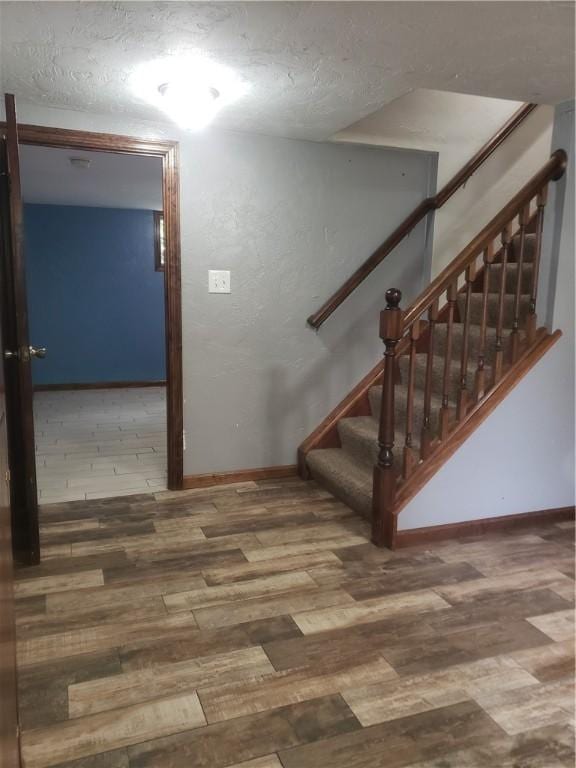 staircase with hardwood / wood-style flooring and a textured ceiling