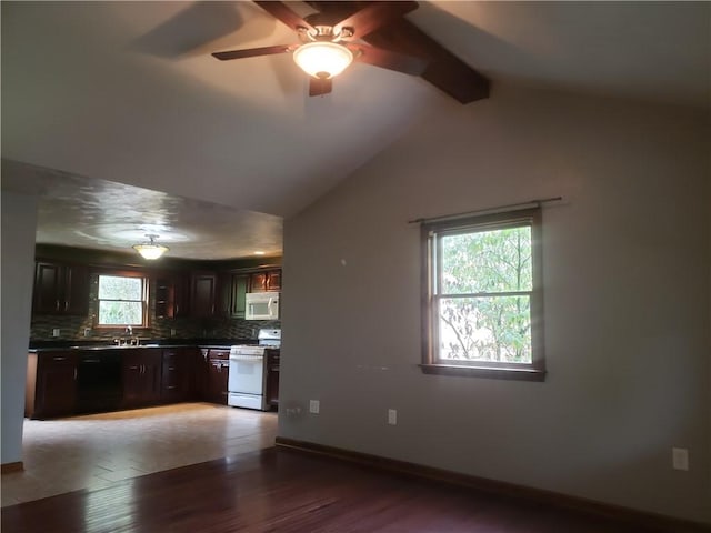 kitchen with tasteful backsplash, lofted ceiling with beams, dark brown cabinets, white appliances, and hardwood / wood-style floors