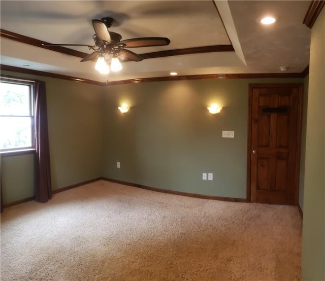 spare room with a raised ceiling, crown molding, light carpet, and ceiling fan