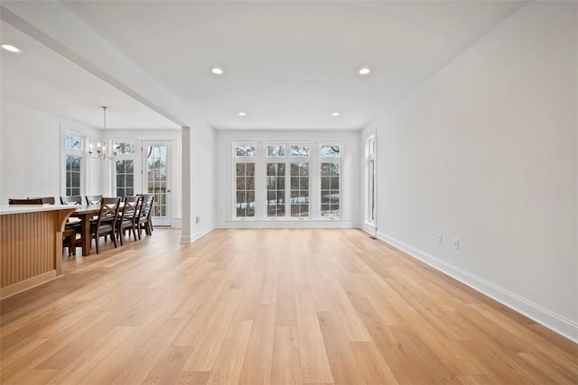 unfurnished living room with a notable chandelier and light hardwood / wood-style flooring