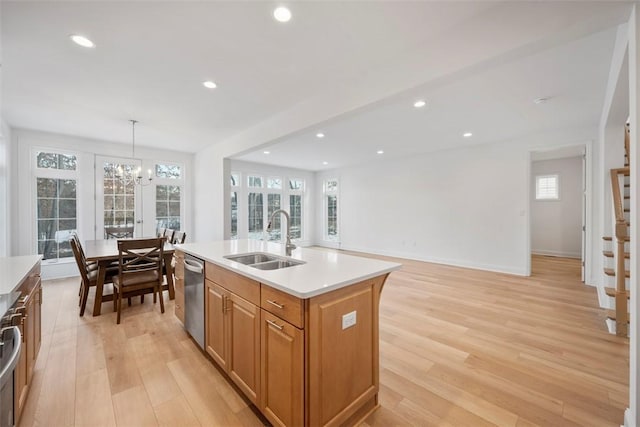 kitchen featuring sink, light hardwood / wood-style flooring, hanging light fixtures, an island with sink, and stainless steel dishwasher