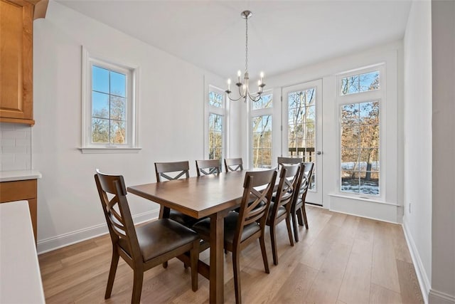 dining space with plenty of natural light, light hardwood / wood-style flooring, and a notable chandelier