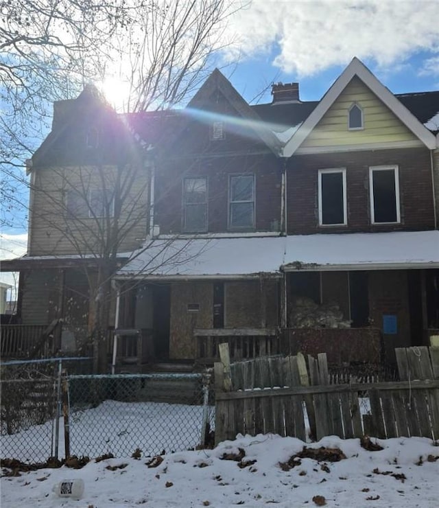 snow covered back of property with covered porch