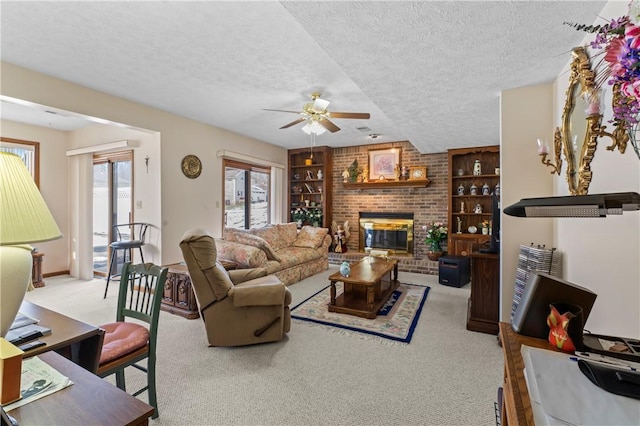 living room featuring built in shelves, a textured ceiling, ceiling fan, light colored carpet, and a fireplace